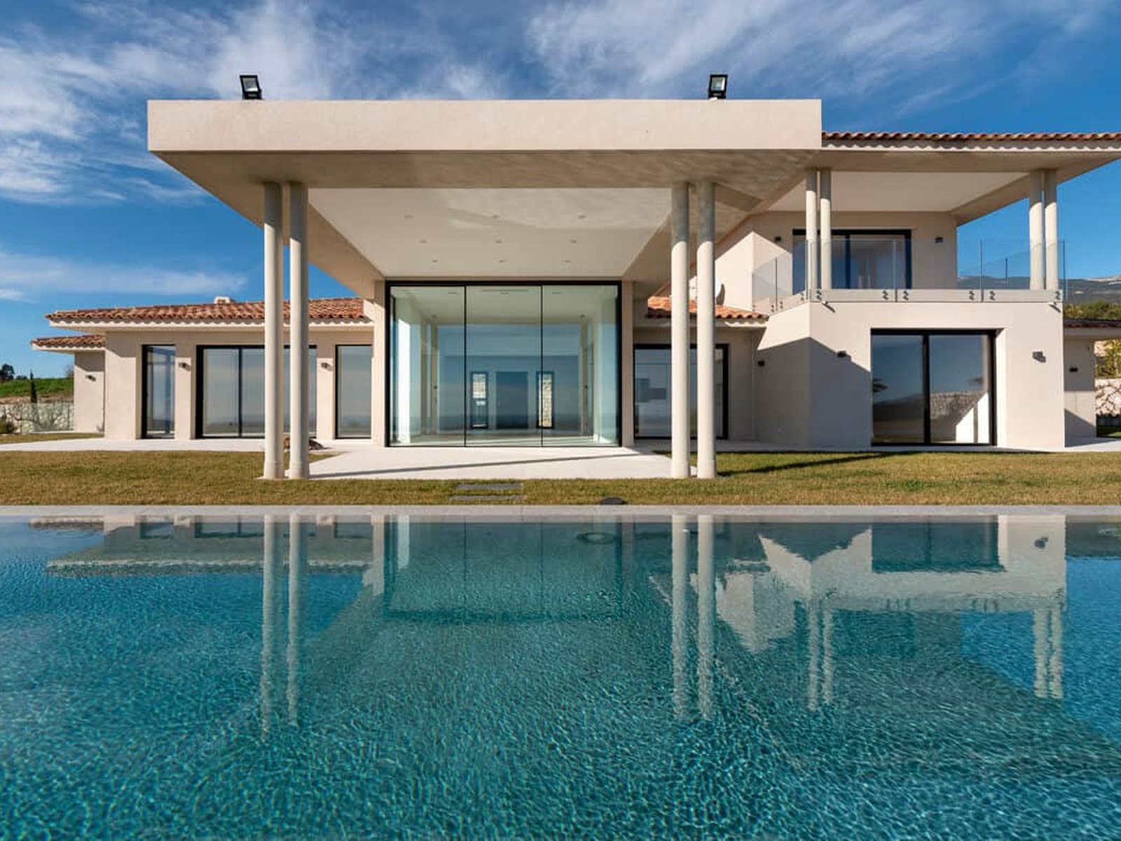A wide run of sliding glass doors along a villa elevation above a pool terrace